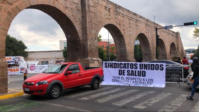 Sindicatos de salud mantendrán bloqueos en Madero, Acueducto y Ventura Puente Por segundo día consecutivo, agremiados a los sindicatos del sector salud mantienen bloqueos en Avenida Acueducto, Ventura Puente y el Congreso del Estado, como parte de un plantón en protesta por el incumplimiento de acuerdos previamente establecidos con las autoridades estatales. Pablo Figueroa Saavedra, agremiado al Sindicato de Médicos, Enfermeras, Trabajadores y Administrativos del Sector Salud (SIMETRA), explicó que la manifestación responde a la falta de cumplimiento en el proceso de escalafón, el cual —aseguró— ha estado marcado por corrupción y retrasos que afectan a más de 3 mil trabajadores. “Estamos en este plantón manifestándonos por el incumplimiento de las autoridades para los acuerdos que ya se tuvieron en una mesa de diálogo anterior. Los principales motivos son el proceso de escalafón de manera oportuna y sin corrupción, porque hemos visto que sí se han dañado nuestros derechos por la antigüedad”, señaló. El representante sindical detalló que los bloqueos viales en Morelia permanecerán hasta que el gobierno estatal instale una mesa de diálogo con los sindicatos unidos de salud, con el objetivo de atender las demandas laborales y garantizar transparencia en los procesos de promoción y reconocimiento de antigüedad.